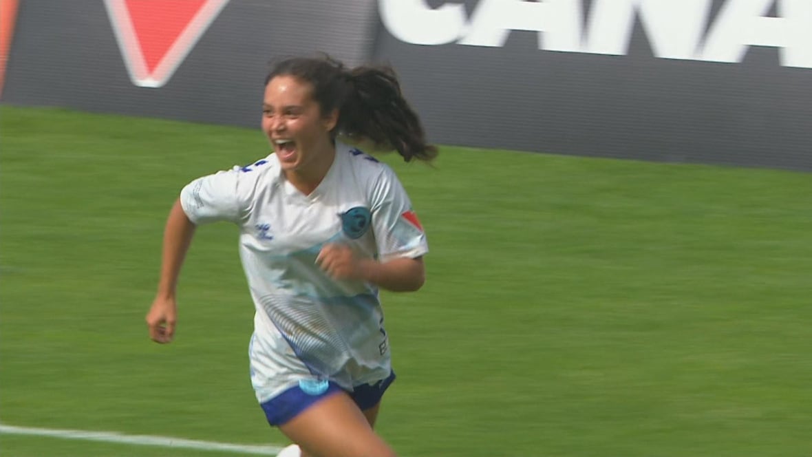 A female soccer player shouts and runs in celebration after scoring.