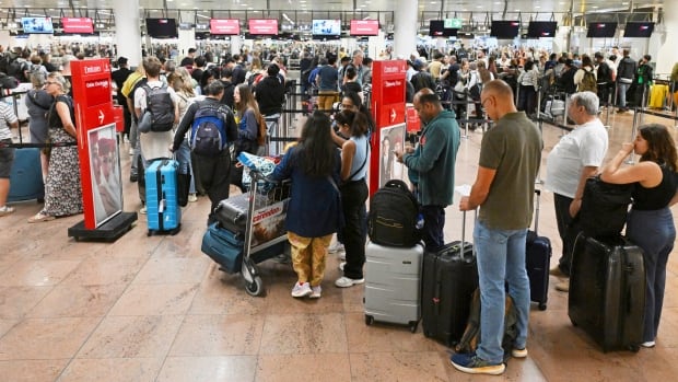 People stand in line inside an airport.