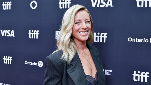 a blonde woman in a blazer smiles at the camera