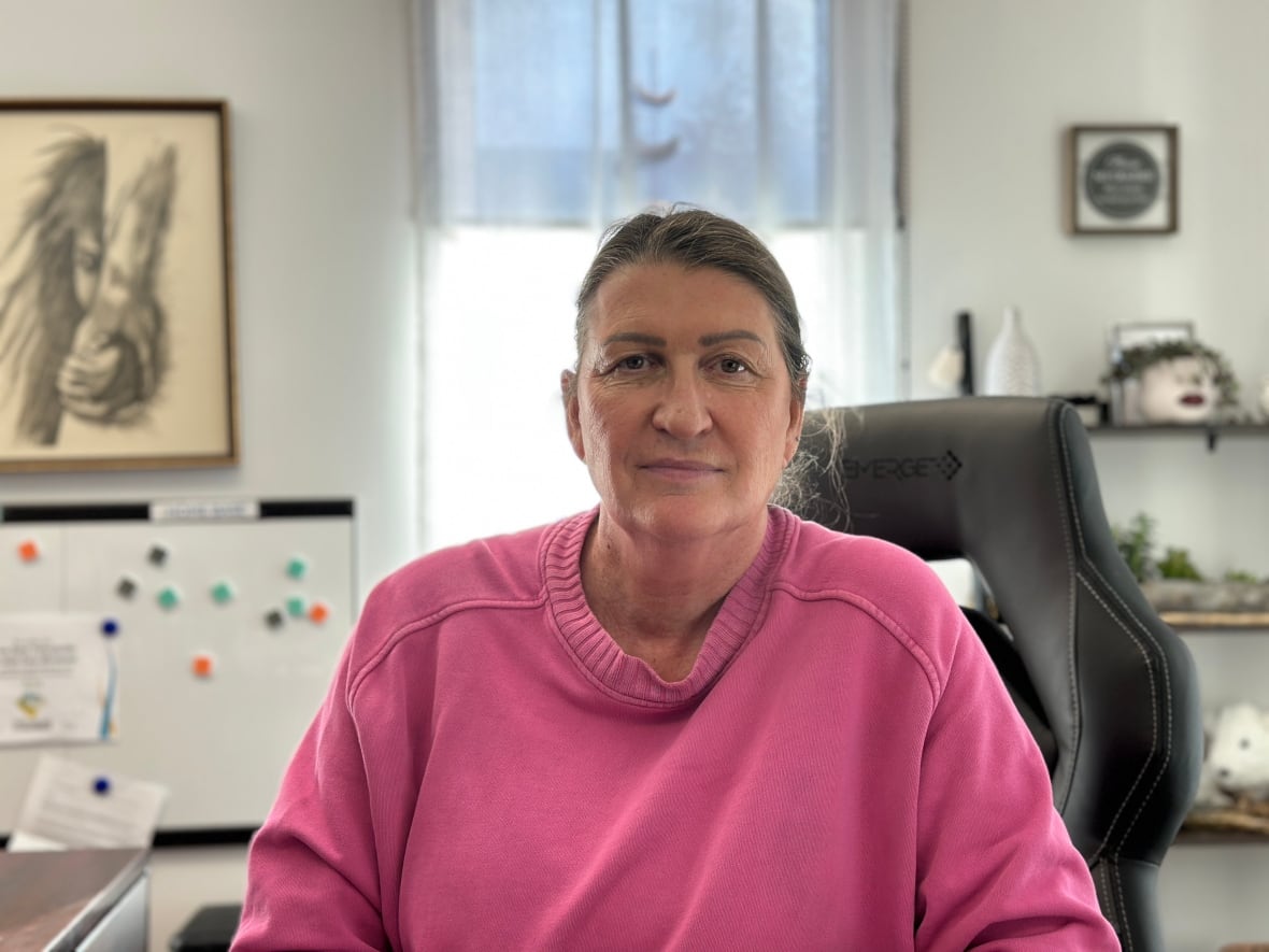 A woman in a pink sweater stares forward.