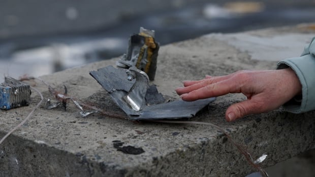A person touches wreckage.
