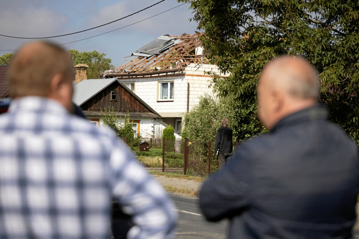 Two men look at a devastating roof.