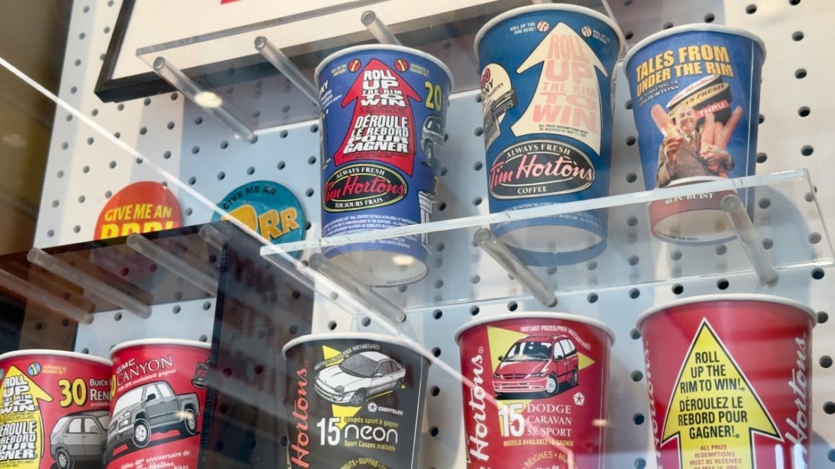 A variety of coffee cups with Tim Hortons Roll Up The Rim branding in a glass display case. 