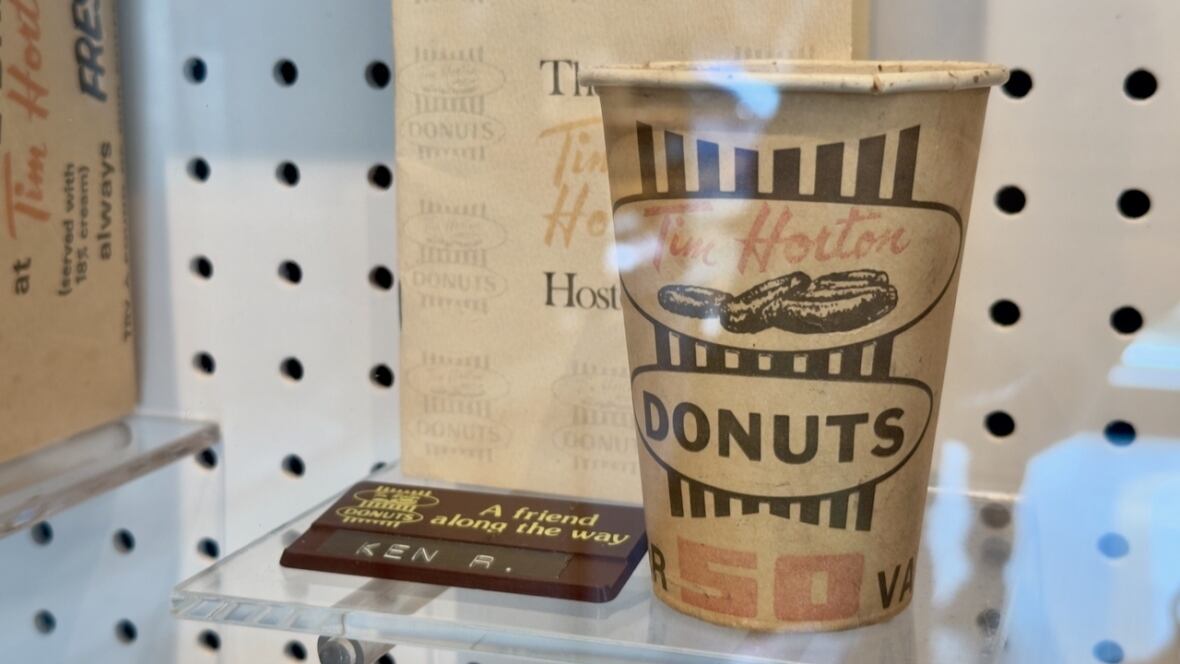 A brown "Tim Horton" coffee cup behind a display case.
