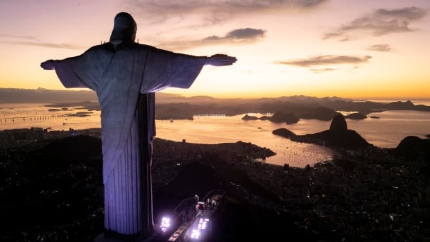 A large statue of Jesus faces a sunrise.