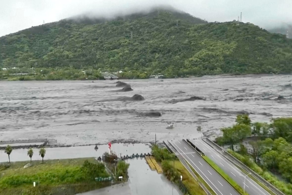 A bridge is partially submerged by water, with a mountain shown in the background.