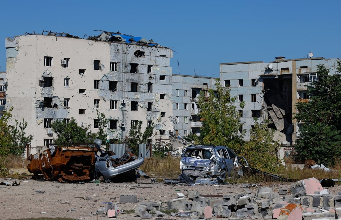 Captive vehicles, one of which is displayed in the front of a picture showing a low -height residential building that was severely damaged.