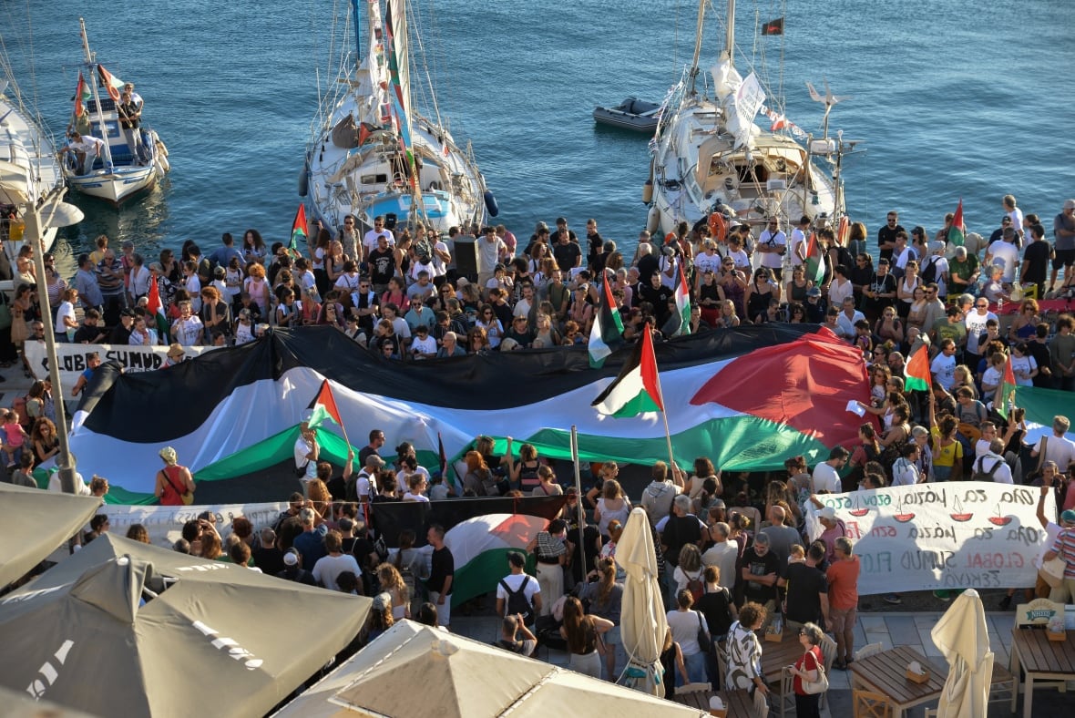 A Palestinian flag is considered to be people gather at the port.
