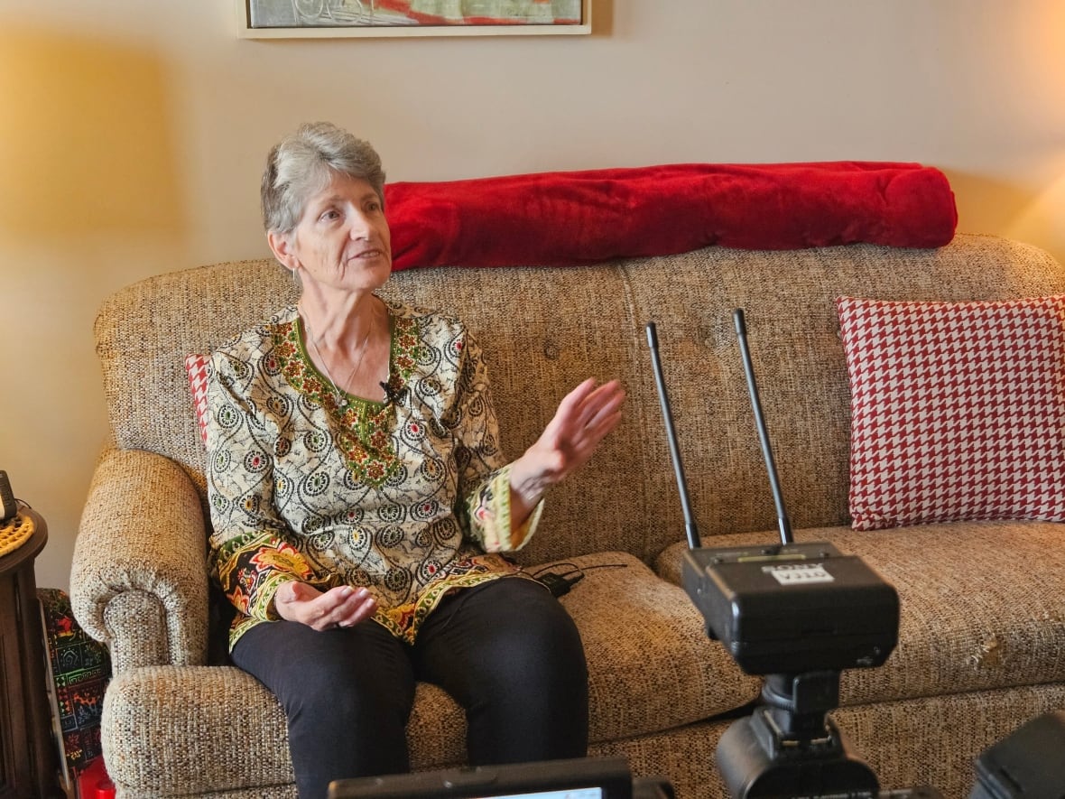 An older woman sits on a couch