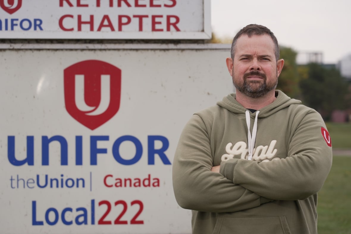 Photo of a man in a green hoodie standing by a sign that reads Unifor Local 222