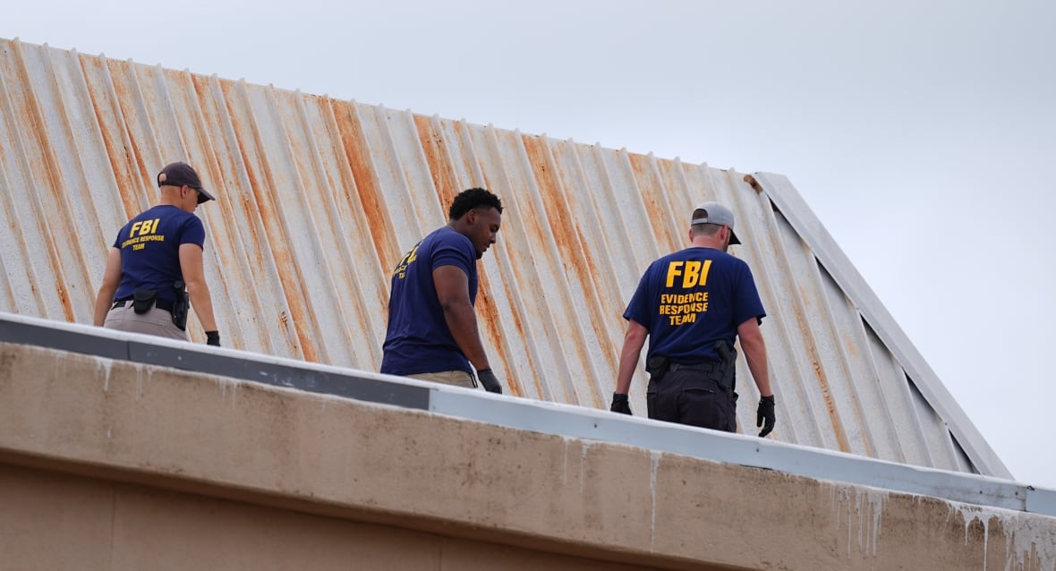 Three people carrying shirts that say that the FBI on the back is walked on a roof. 