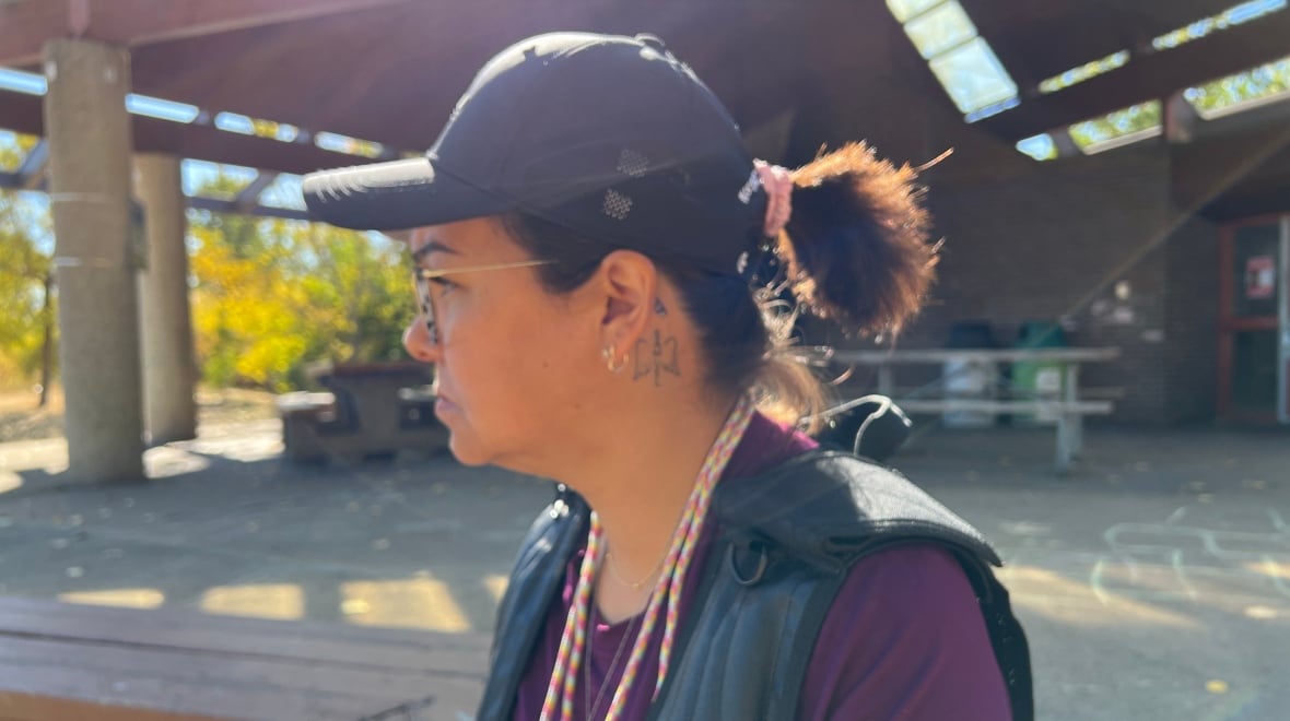 A woman posed in profile, displaying a small tattoo behind her ear. 