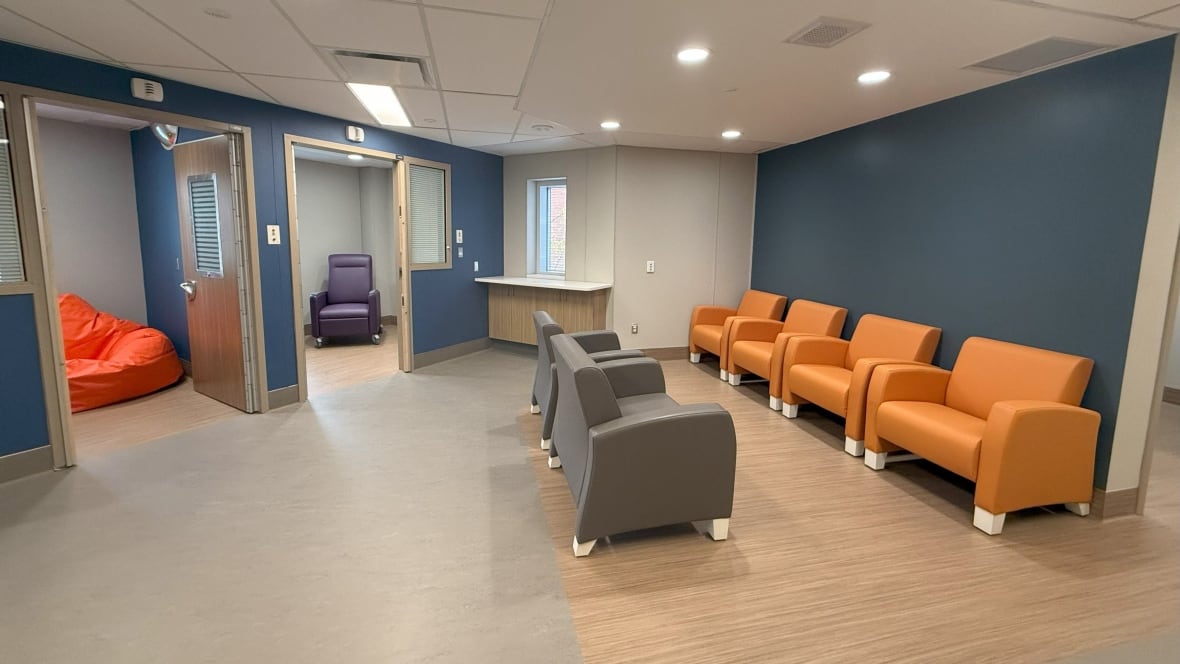 Una piccola sala d'attesa medica con pareti blu. Si vedono due sale per trattamenti con porte aperte, una con una poltrona per trattamenti e l'altra con una poltrona a sacco.