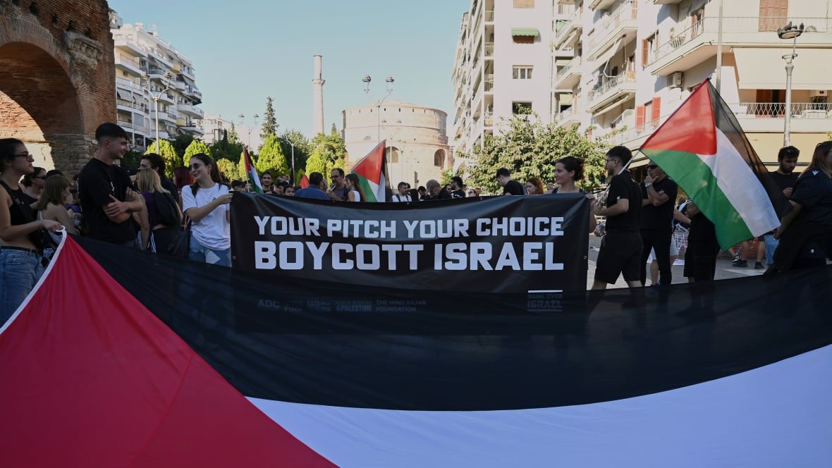 Protestors hold a sign that says your pitch your choice, boycott Israel