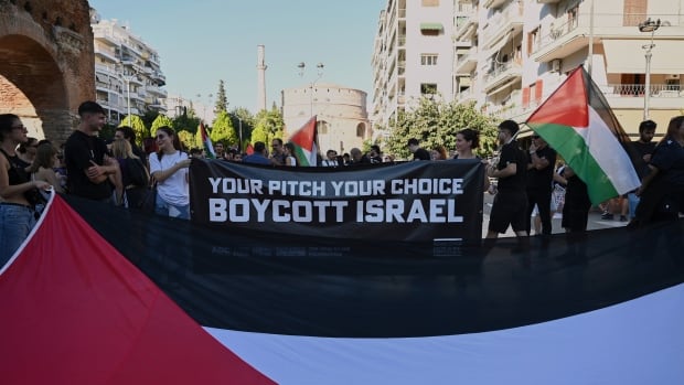 Protestors hold a sign that says your pitch your choice, boycott Israel