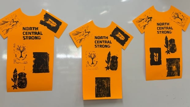 A picture of orange shirts cut out and stamped with linocut art work
