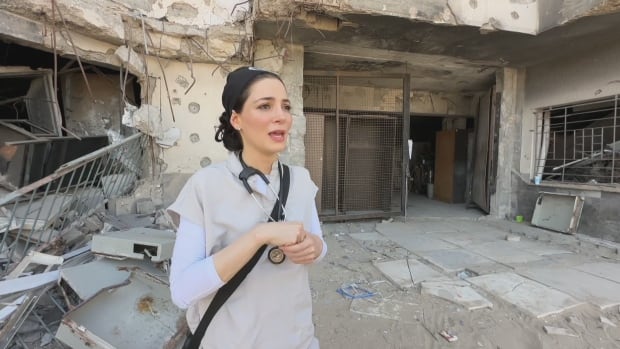 a woman stands in front of rubble