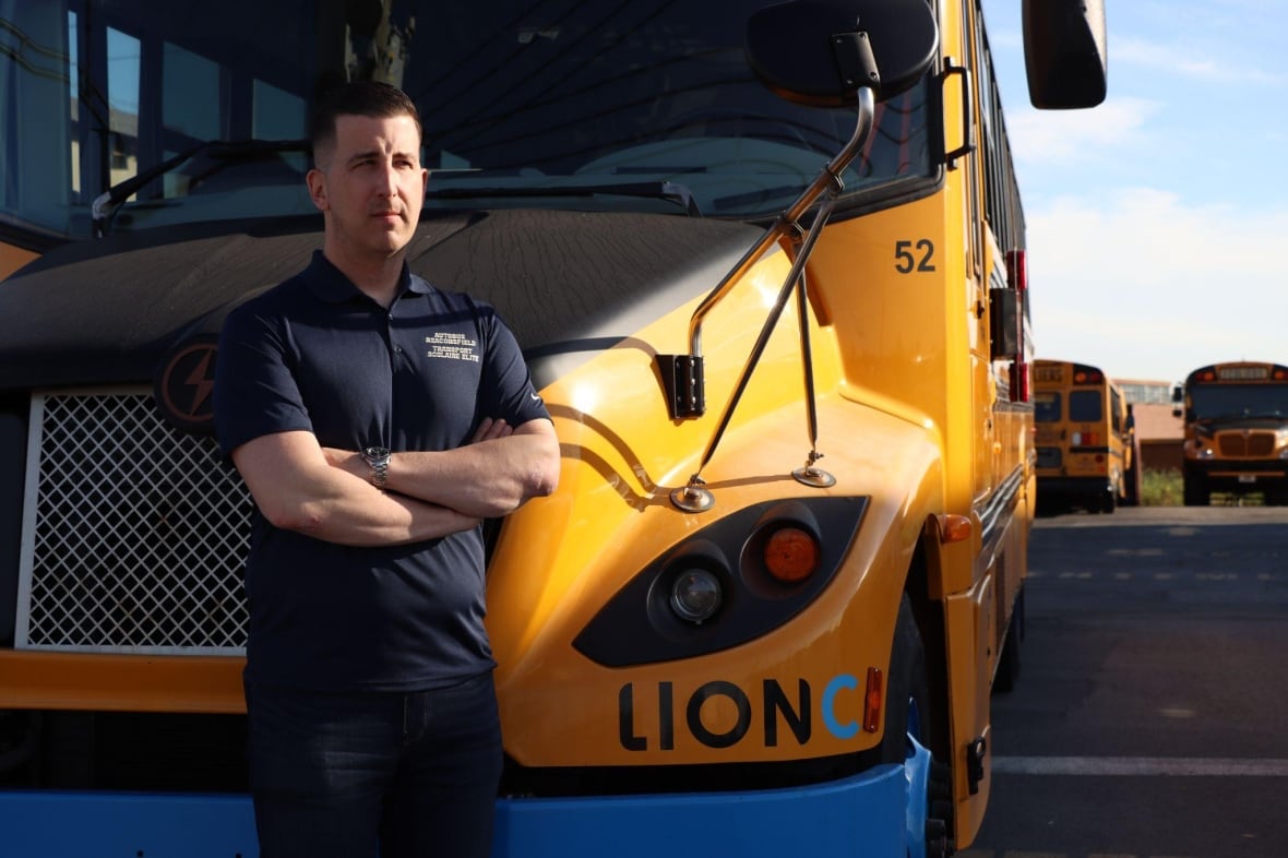 A man standing in front of a school bus. 