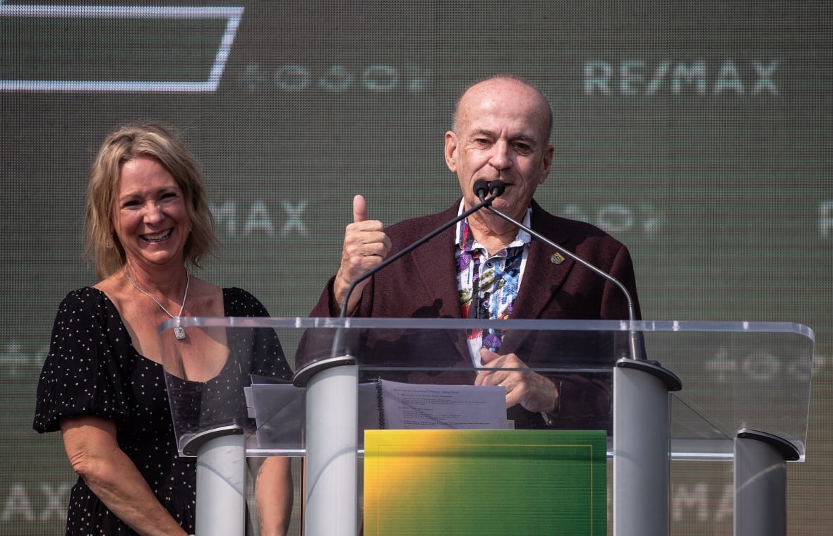 A woman and a man stand in front of a stadium.