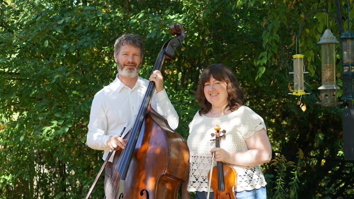 Two people stand with instruments in their backyard.