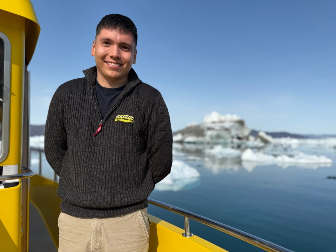 A short brown hair man wearing a black sweater smiles for a photo.