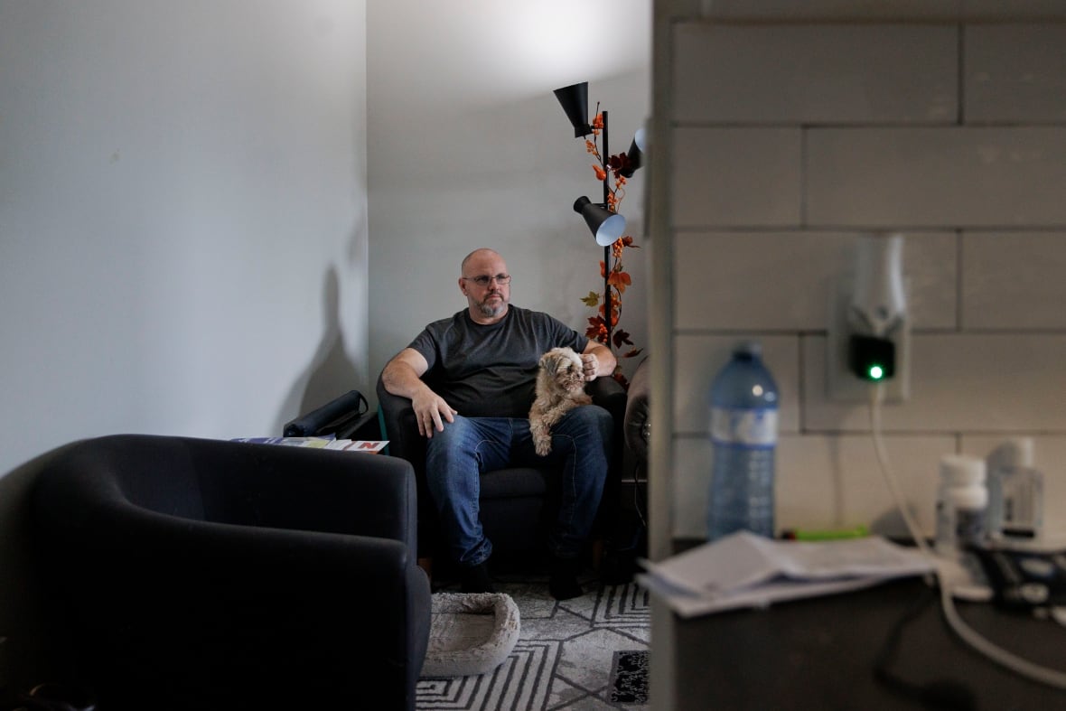 Man in his apartment sitting his dog. 