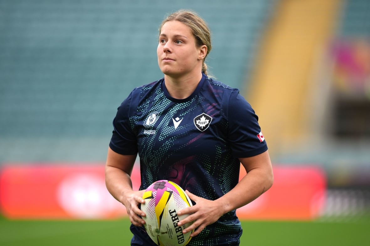 Uma mulher segura uma bola de rugby