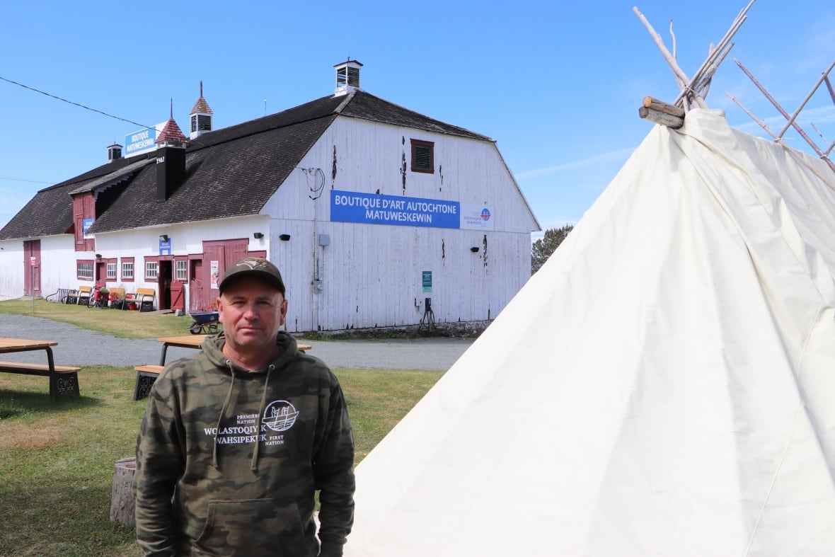 A man standing next to a structure and in front of a boutique. 