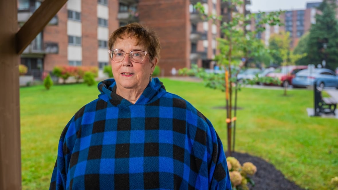 A woman stands in front of an apartment complex.