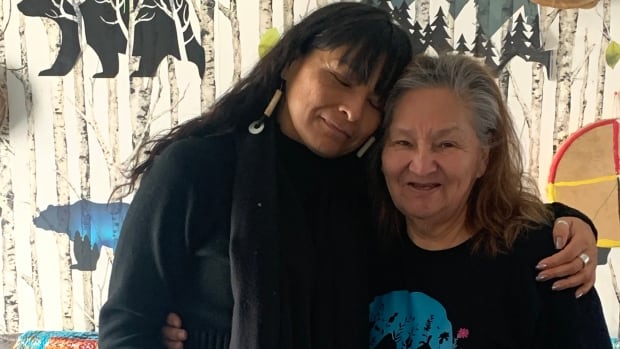 Leticia stands next to Linda and leans her head against Linda who's smiling.