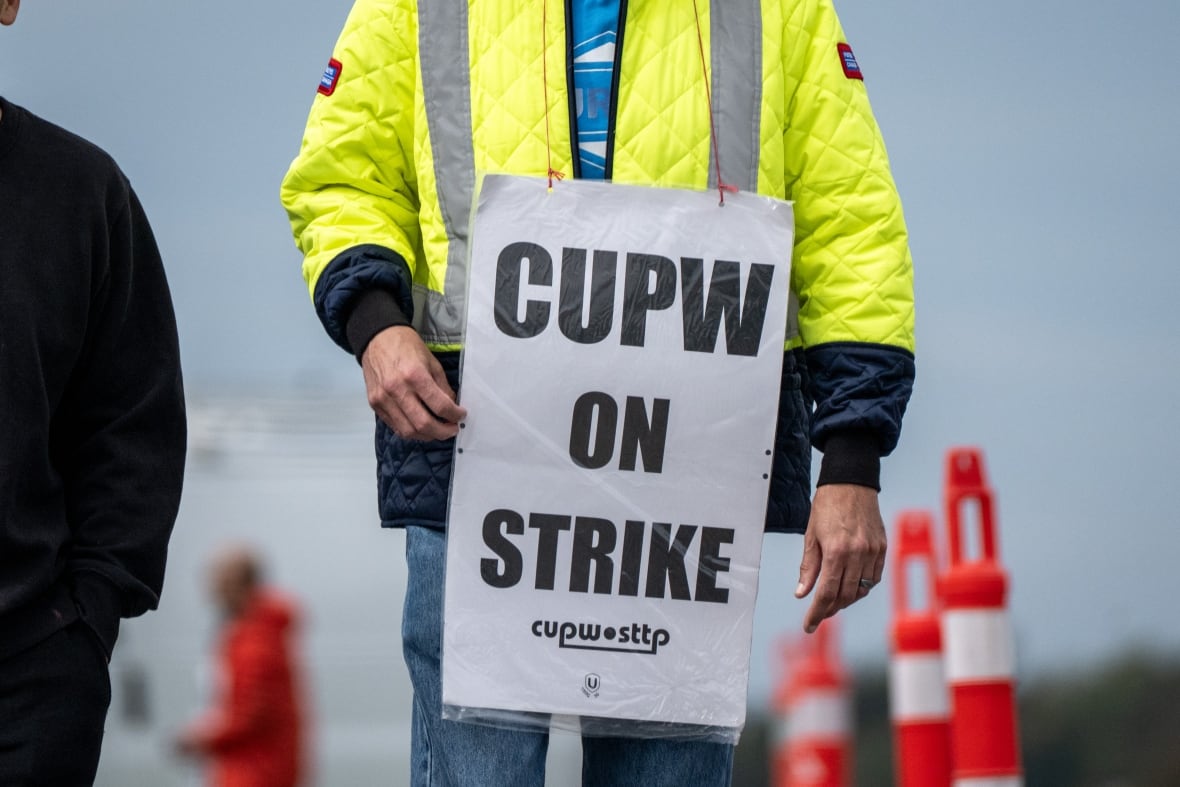 A closeup shows a person in a yellow jacket with a sign reading "CUPW on strike."