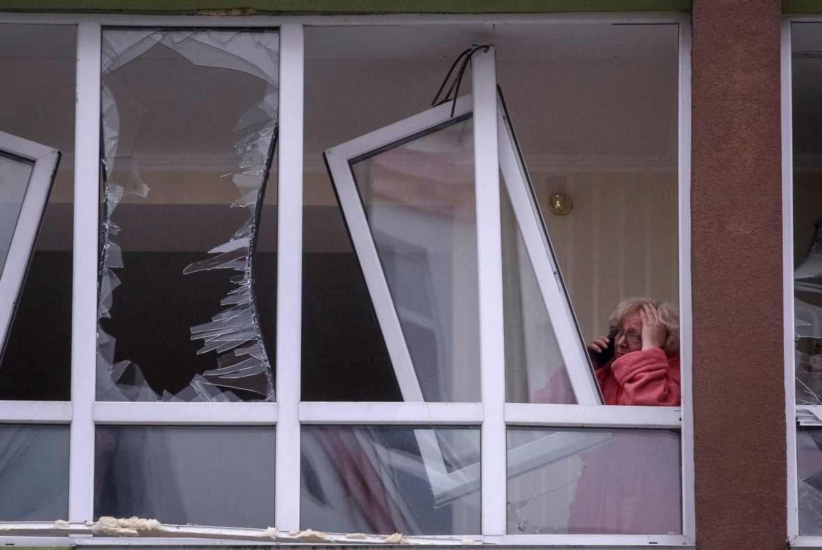 A woman stands in a devastating window with her forehead talking on the phone.