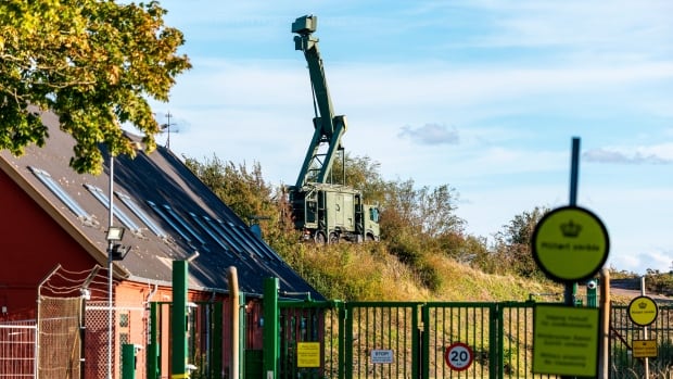 A machine is seen behind bushes. 