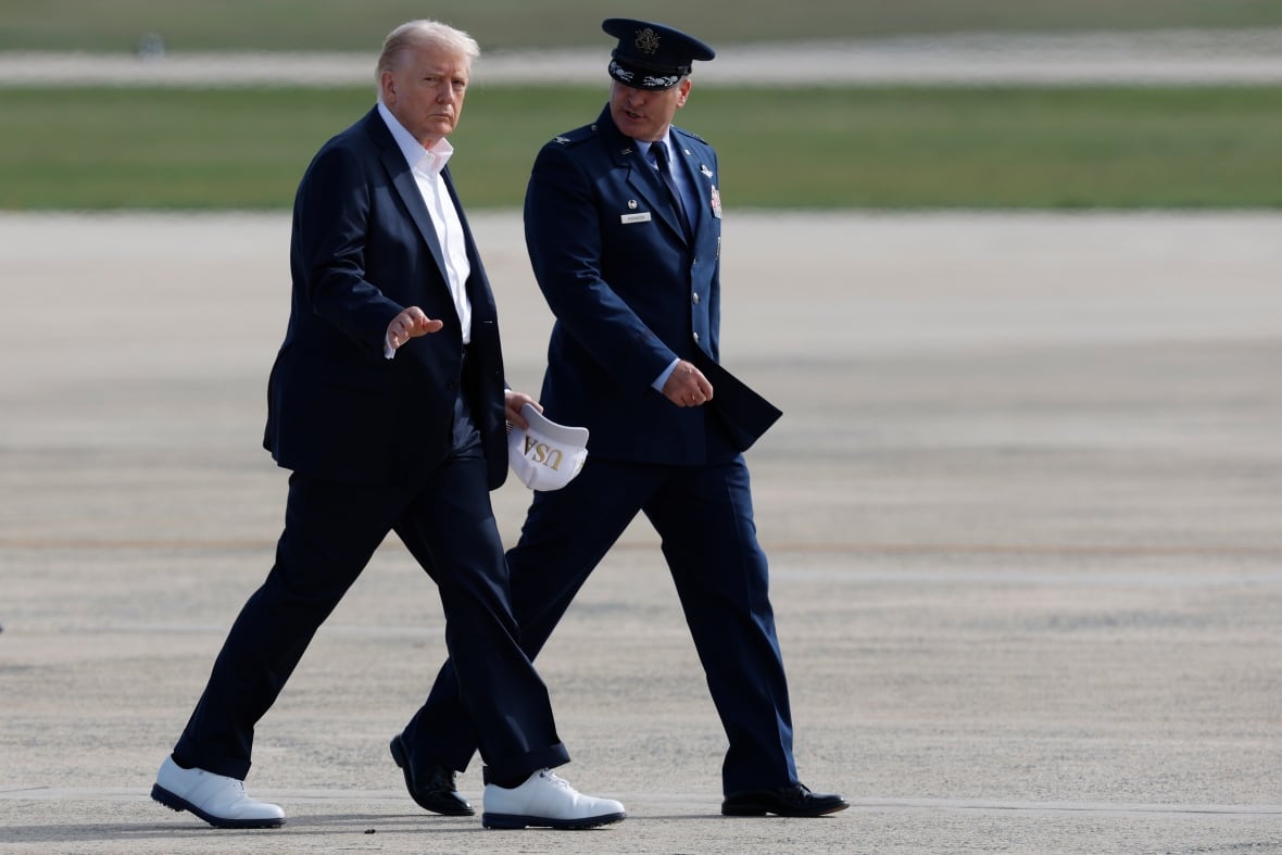Trump wears white golf shoes walking at the airport runway with a military officer wearing the uniform. 