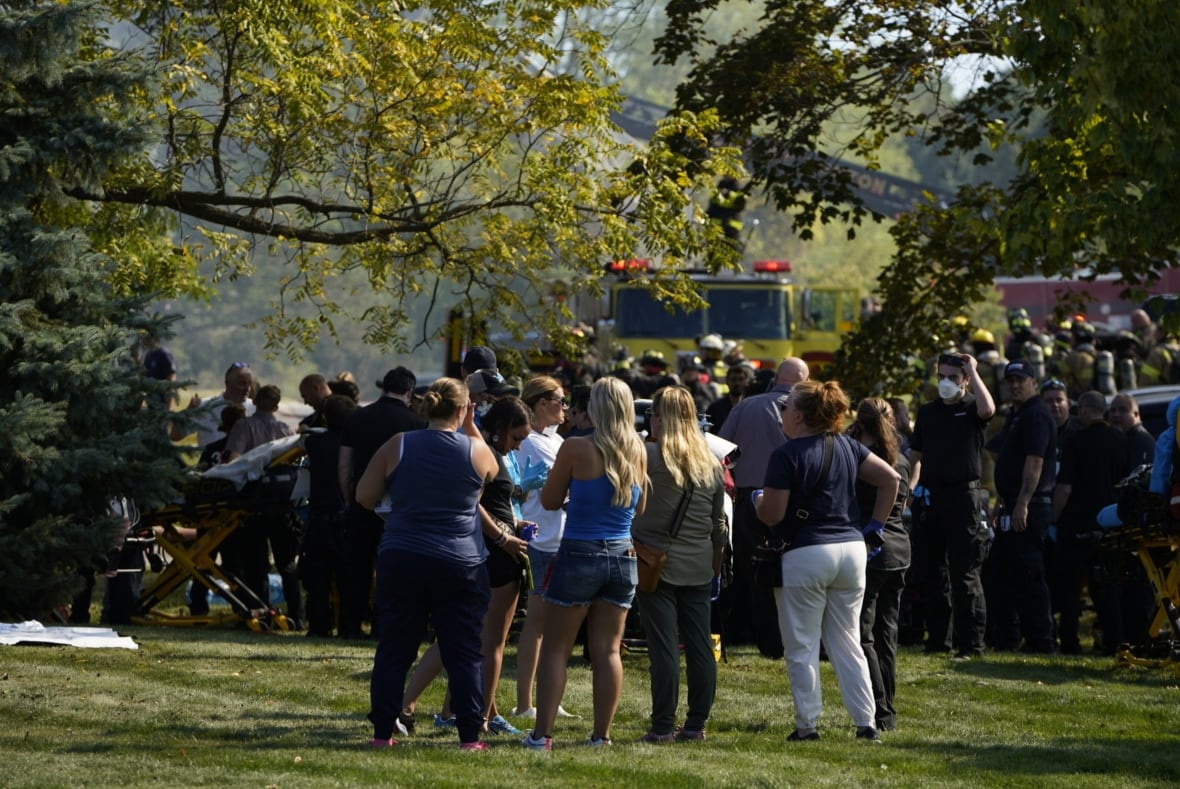 A group of people watch on as emergency responders work outside of a church.