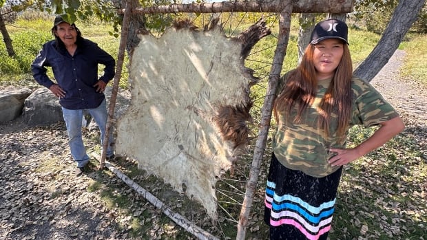 Two people with an elk hide.