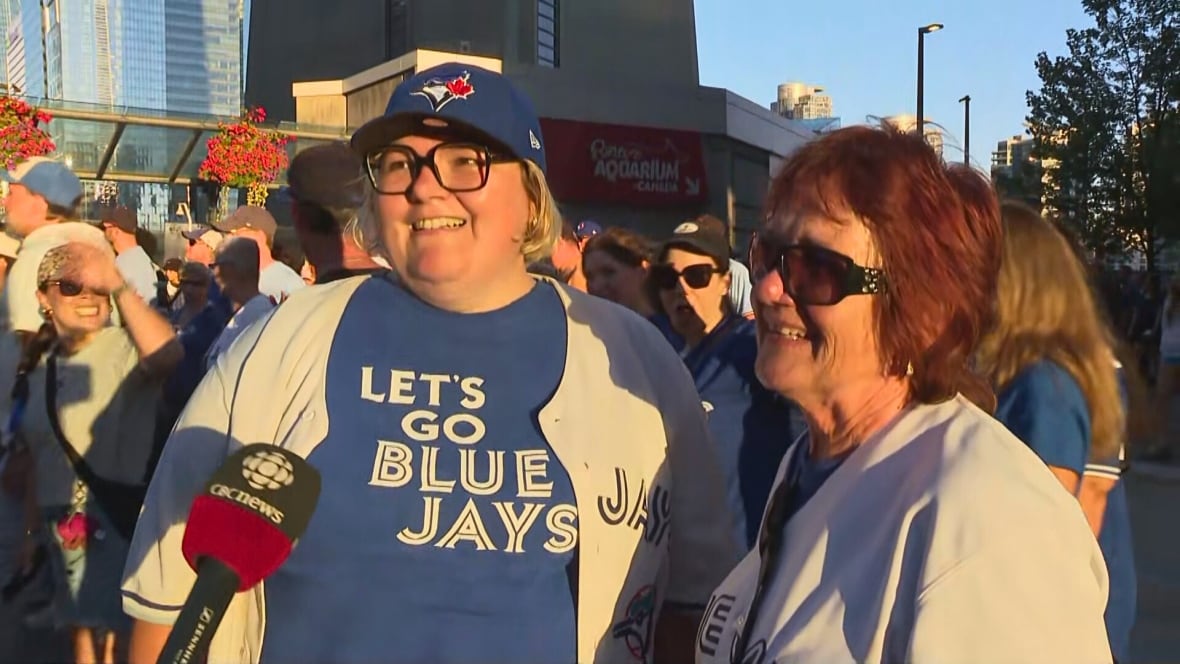 Two woman in baseball jerseys speak to a reporter off camera.