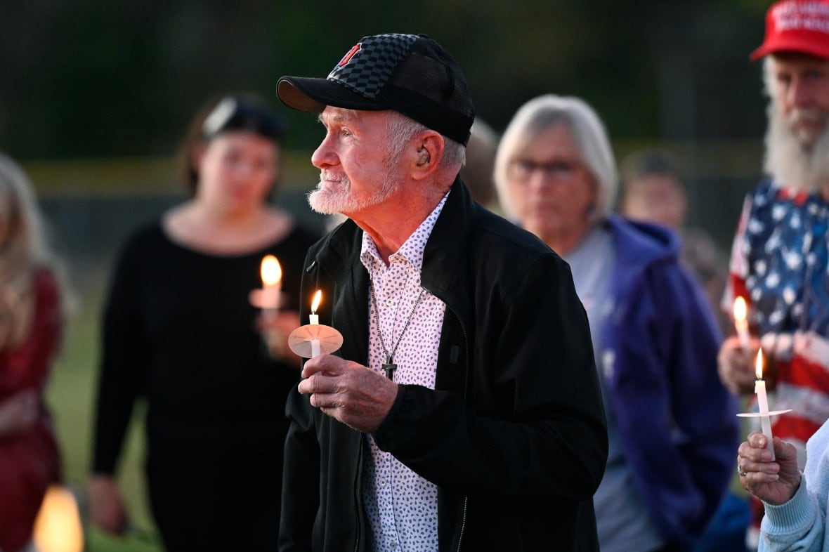The attendees carry their lit candles during the vigil after the shooting of the nearby church in the Peruvian Savior Church in Berton, Michigan, on Sunday, September 28, 2025.