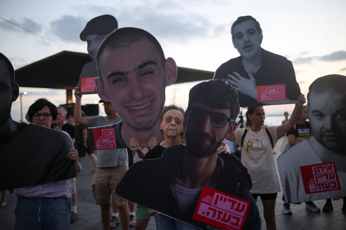 A crowd of demonstrators carrying large pictures of men and women. 