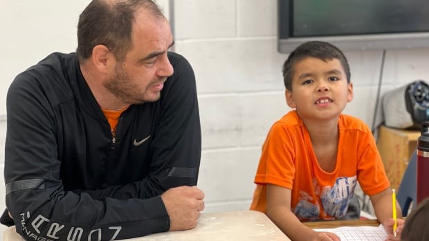 A man and a young boy sit at a desk.