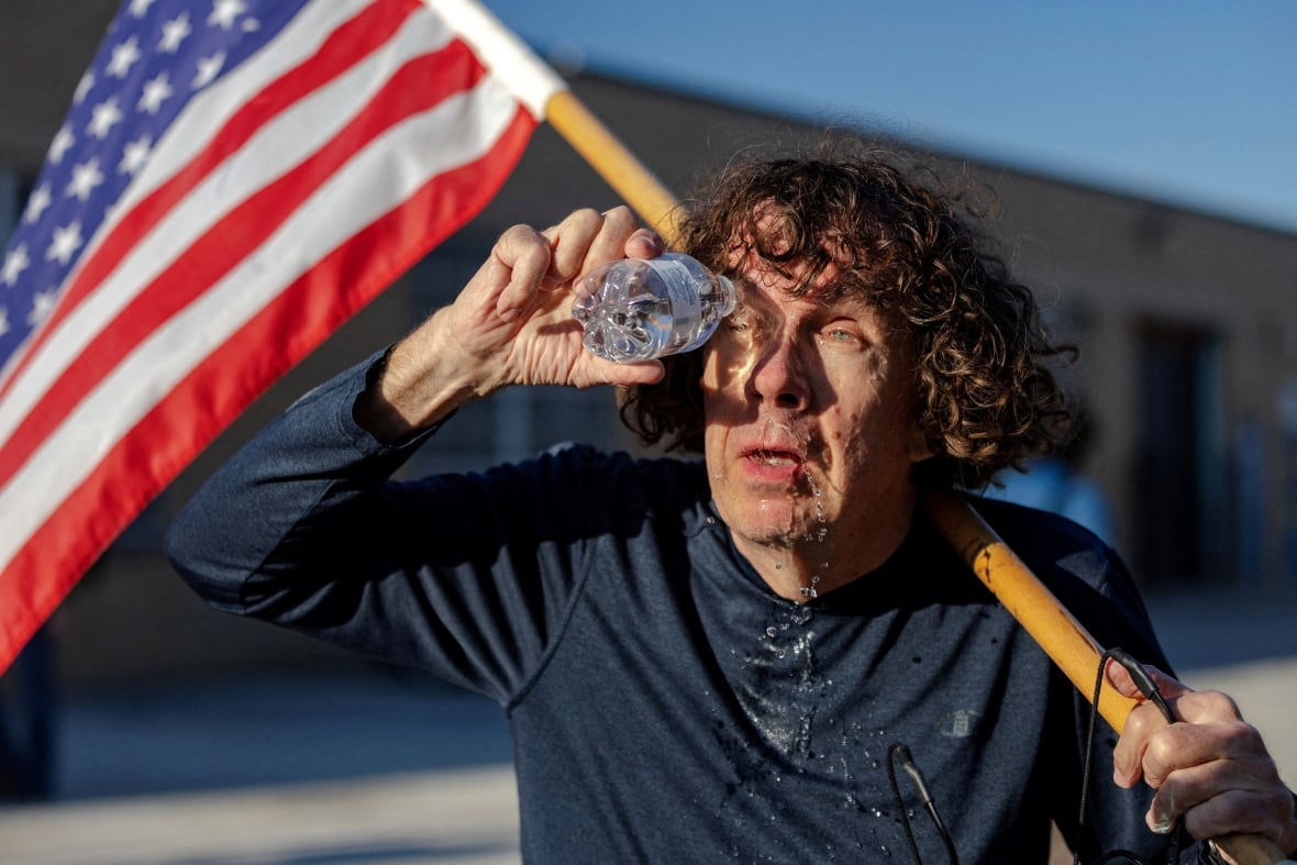 A man expels a chemical irritation from his eyes while he was carrying the American flag.
