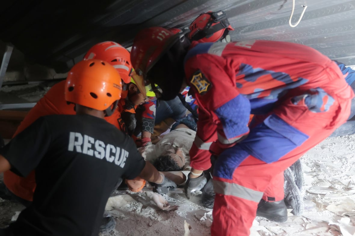 Rescuers pull out a survivor from a collapsed building