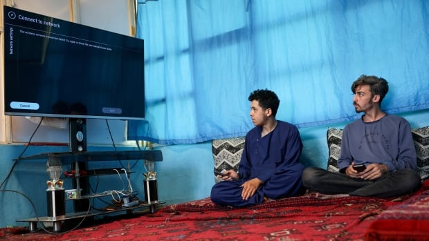 Men try to connect their smart TV to the internet inside their home.