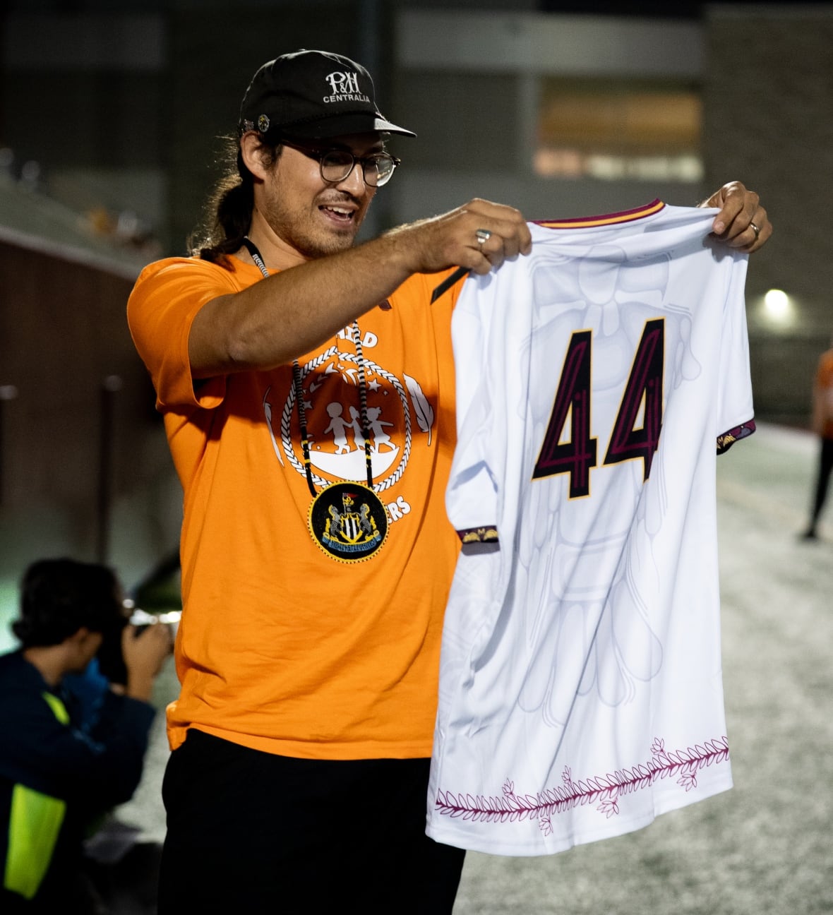 A person outside holds up a jersey with the number 44 on the back.