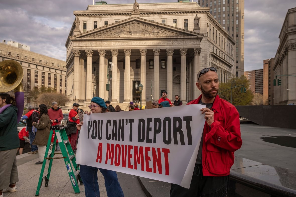 A bearded man holds a banner saying: 