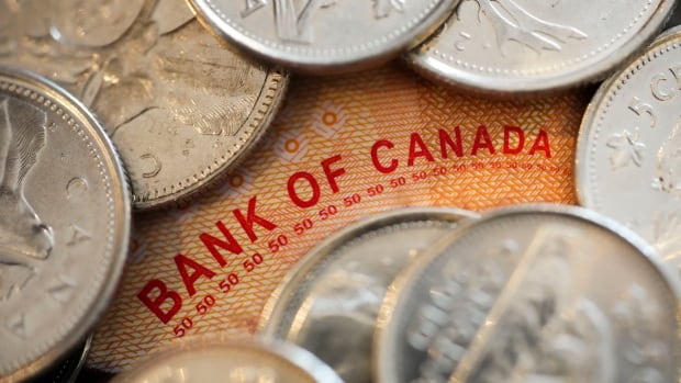 A few coins are spread on a Canadian 50-dollar bill.