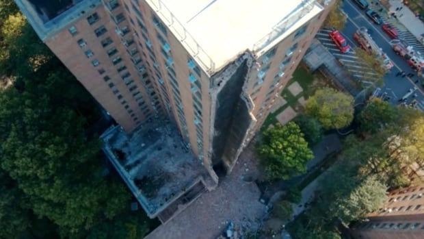 A building is seen from above with part of its siding detached.