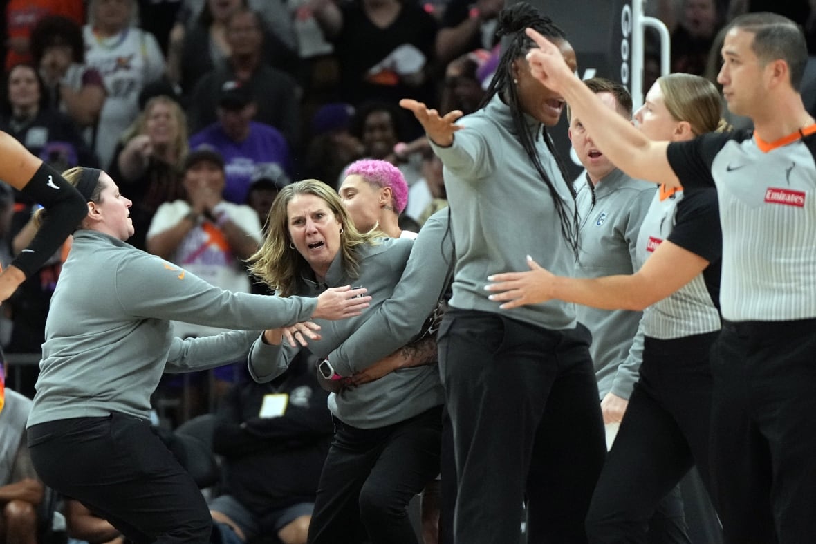 A woman wearing a coach is placed by several other people in the basketball field