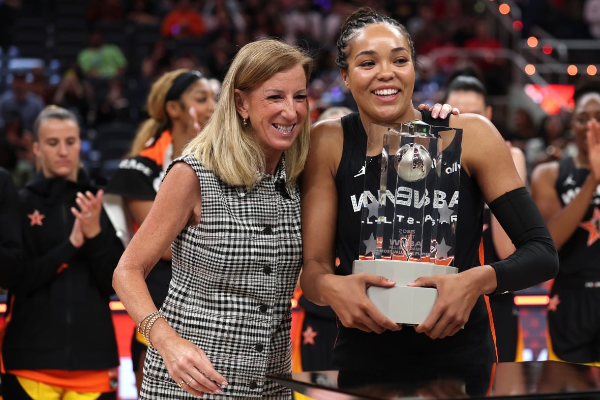 Two women adopt the basketball field. One holds the cup