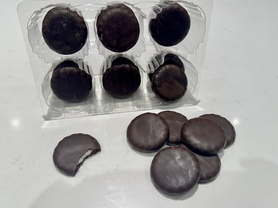 A sleeve of cookies, with one bitten into and others on a table.
